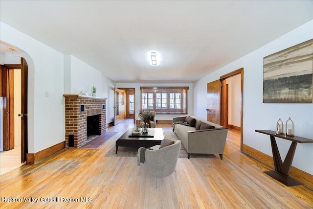 living room with light hardwood / wood-style flooring and a brick fireplace