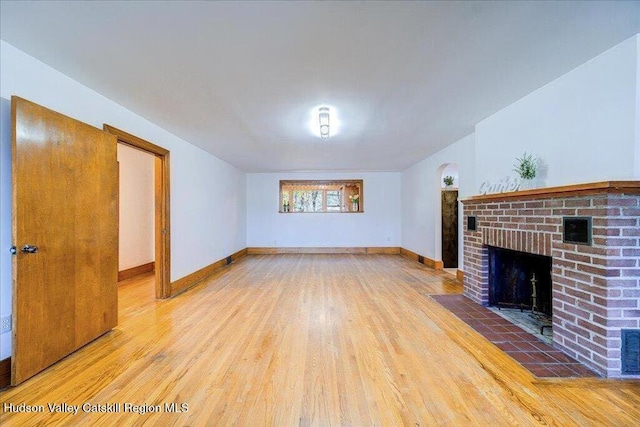 unfurnished living room with hardwood / wood-style floors and a brick fireplace