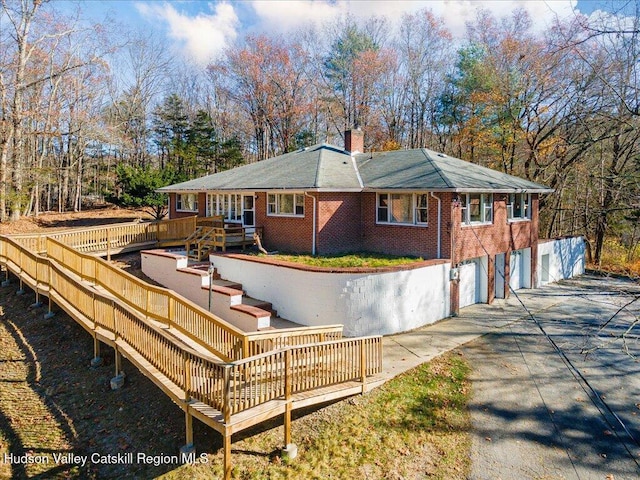 rear view of house with a wooden deck and a garage