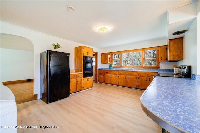 kitchen with sink, black appliances, and light hardwood / wood-style floors