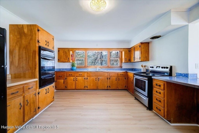 kitchen with stainless steel electric range, light hardwood / wood-style floors, crown molding, and sink