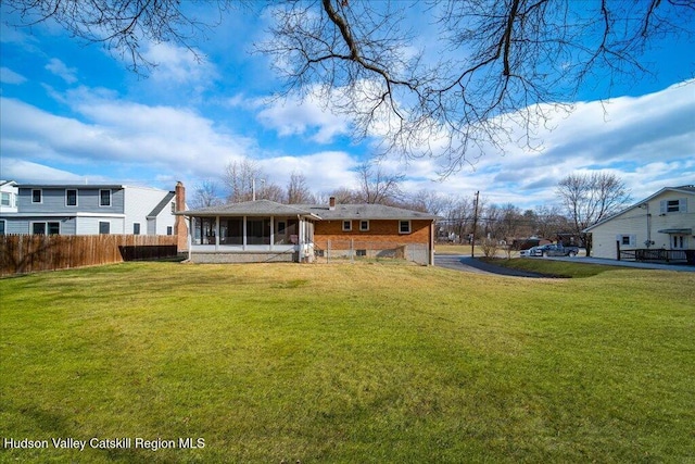 back of house featuring a sunroom and a lawn