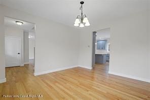 unfurnished room featuring light hardwood / wood-style floors and an inviting chandelier