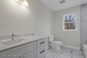 bathroom with vanity, toilet, and a tub to relax in