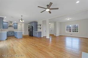 unfurnished living room with ceiling fan with notable chandelier and light wood-type flooring