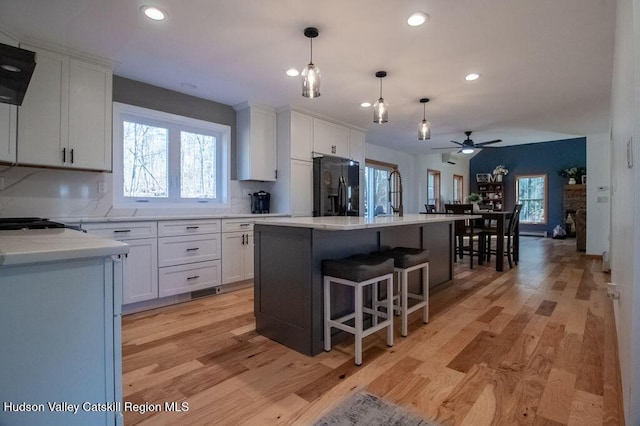 kitchen featuring white cabinetry, black fridge, a kitchen island, and light hardwood / wood-style flooring