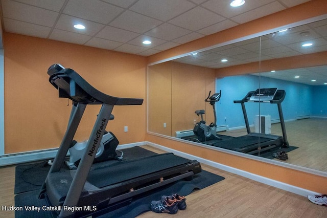 exercise area featuring hardwood / wood-style floors, baseboard heating, and a drop ceiling