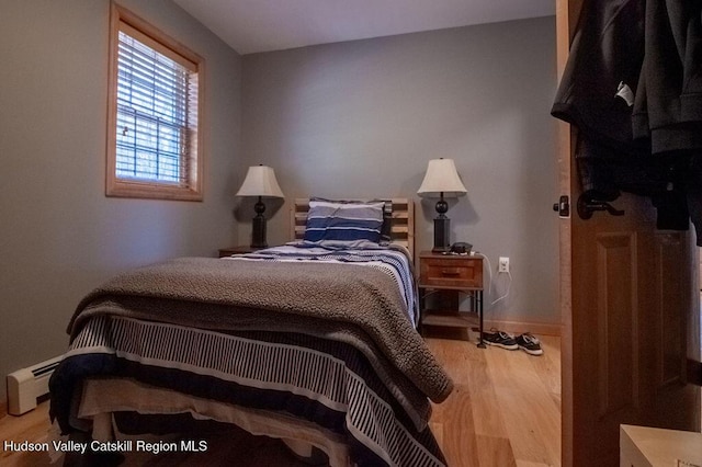 bedroom featuring wood-type flooring and a baseboard radiator