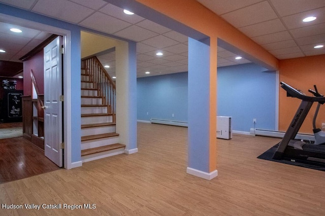 workout room featuring baseboard heating, a drop ceiling, and light hardwood / wood-style floors