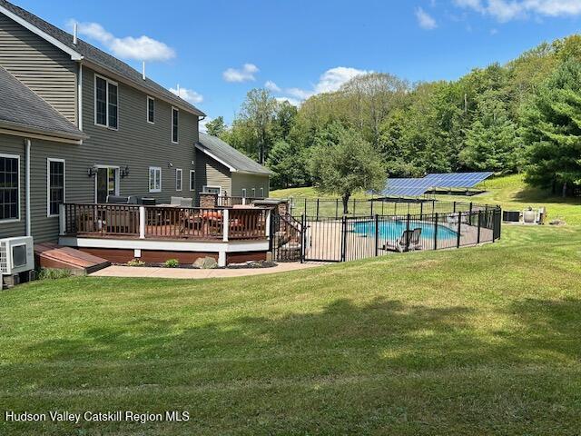 view of swimming pool with ac unit, a deck, and a lawn