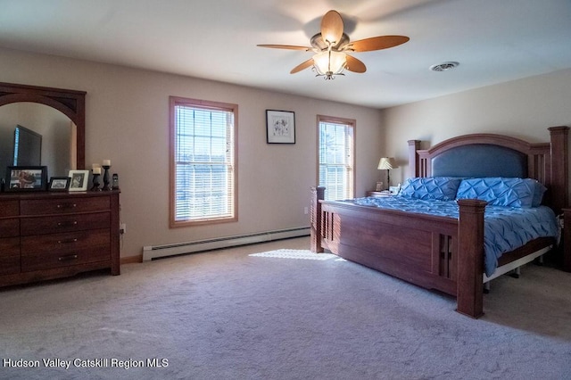 bedroom featuring light colored carpet, multiple windows, a baseboard heating unit, and ceiling fan