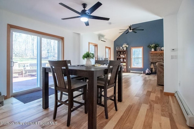 dining space with light hardwood / wood-style floors, vaulted ceiling, an AC wall unit, and a baseboard heating unit