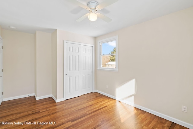 unfurnished bedroom with ceiling fan, wood-type flooring, and a closet