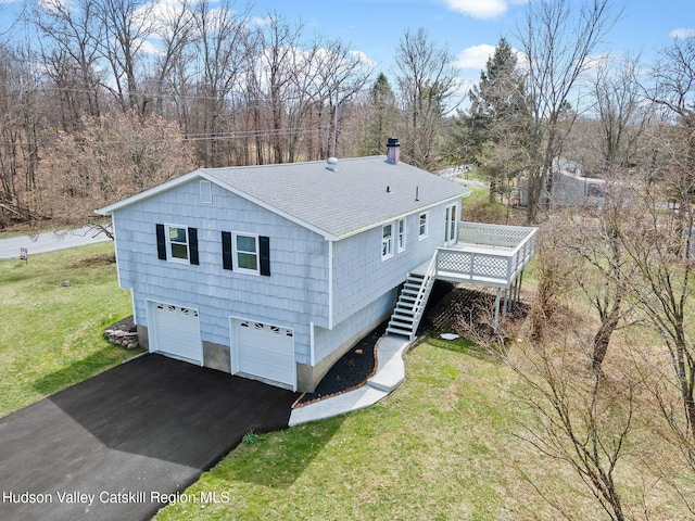 view of side of home featuring stairway, a yard, a wooden deck, driveway, and roof with shingles
