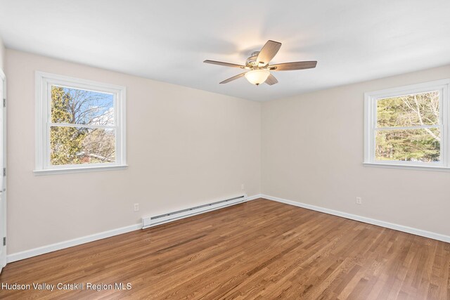 spare room with a baseboard radiator, a healthy amount of sunlight, hardwood / wood-style floors, and ceiling fan