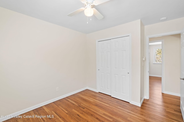 unfurnished bedroom with ceiling fan, a closet, and light wood-type flooring