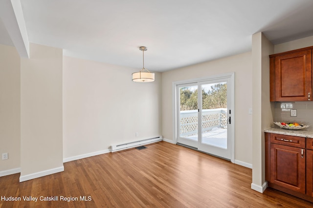 unfurnished dining area with a baseboard heating unit and light hardwood / wood-style floors