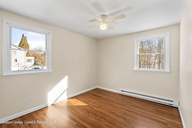 unfurnished room featuring a baseboard radiator, wood-type flooring, and a healthy amount of sunlight