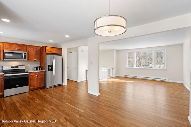 kitchen with hanging light fixtures, stainless steel appliances, light hardwood / wood-style floors, and baseboard heating