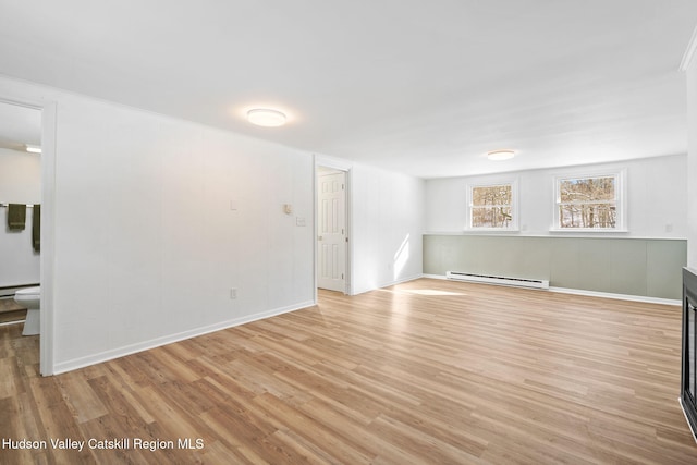 empty room with baseboard heating and light hardwood / wood-style floors