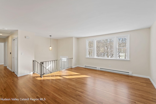 unfurnished room with wood-type flooring and a baseboard heating unit