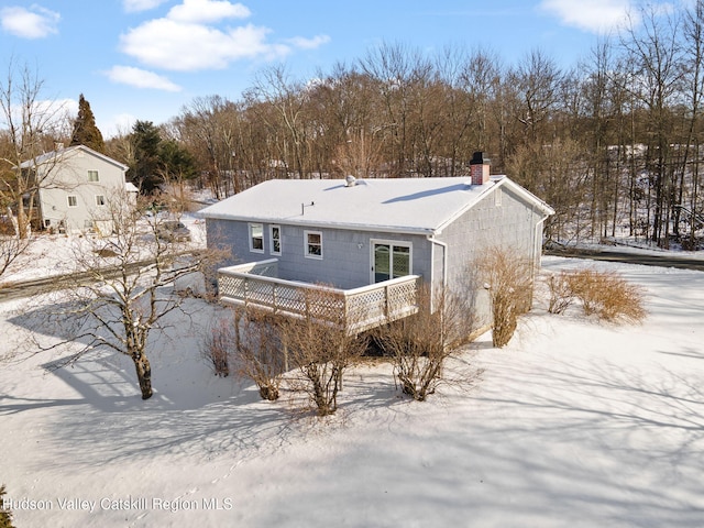 snow covered back of property with a deck