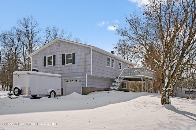 snow covered property featuring a wooden deck and a garage