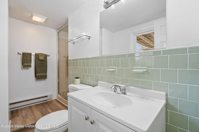 bathroom featuring a shower with door, tile walls, vanity, a baseboard radiator, and toilet