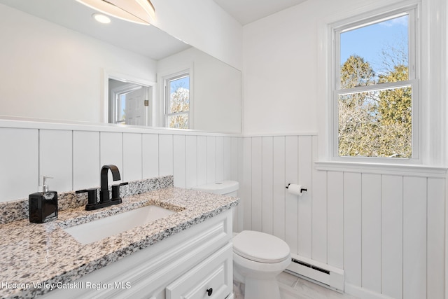 bathroom featuring vanity, plenty of natural light, baseboard heating, and toilet