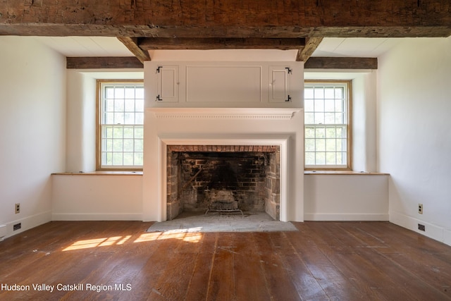 unfurnished living room featuring a wealth of natural light, beamed ceiling, and dark hardwood / wood-style floors