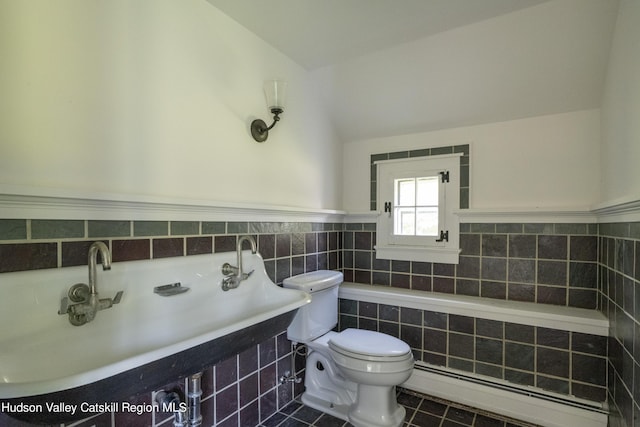 bathroom featuring vaulted ceiling, a baseboard radiator, tile walls, tile patterned flooring, and toilet