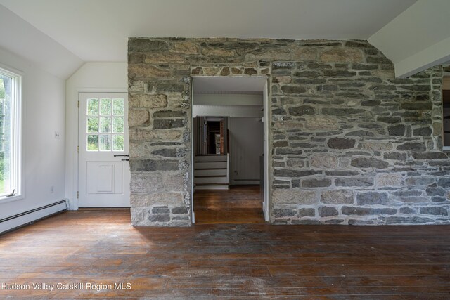 unfurnished living room featuring dark hardwood / wood-style floors, a baseboard heating unit, and vaulted ceiling