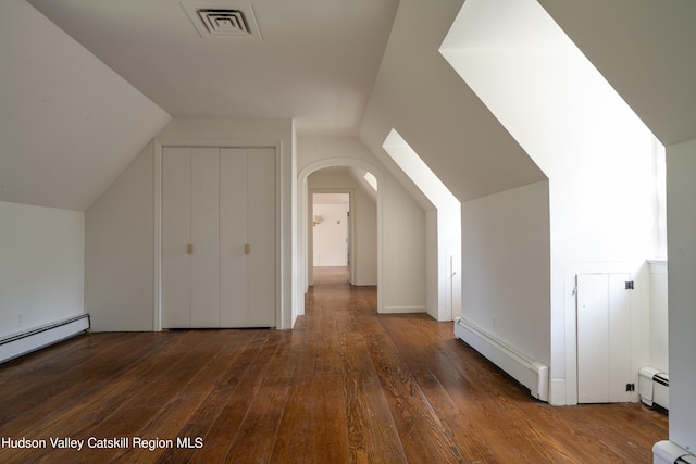 additional living space featuring lofted ceiling, dark hardwood / wood-style floors, and a baseboard heating unit