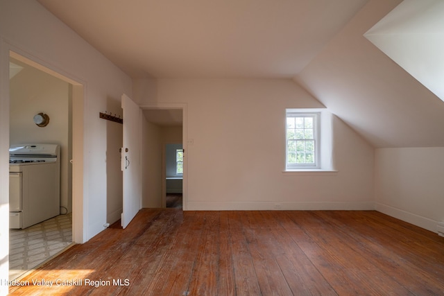 additional living space featuring washer / dryer, light hardwood / wood-style floors, and vaulted ceiling