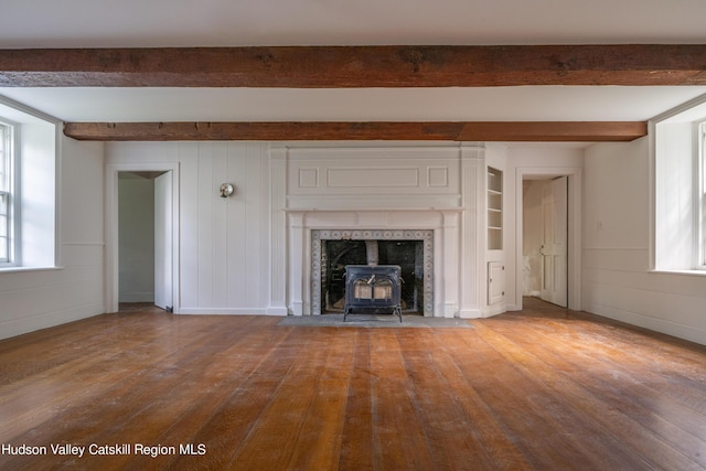 unfurnished living room featuring a wood stove, beamed ceiling, and hardwood / wood-style flooring