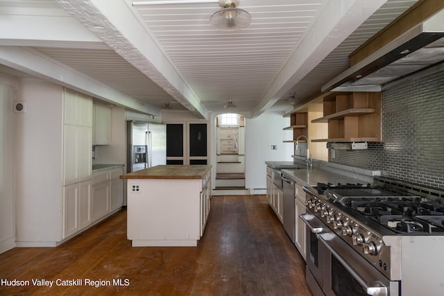 kitchen featuring dark wood-type flooring, decorative backsplash, appliances with stainless steel finishes, a kitchen island, and butcher block counters