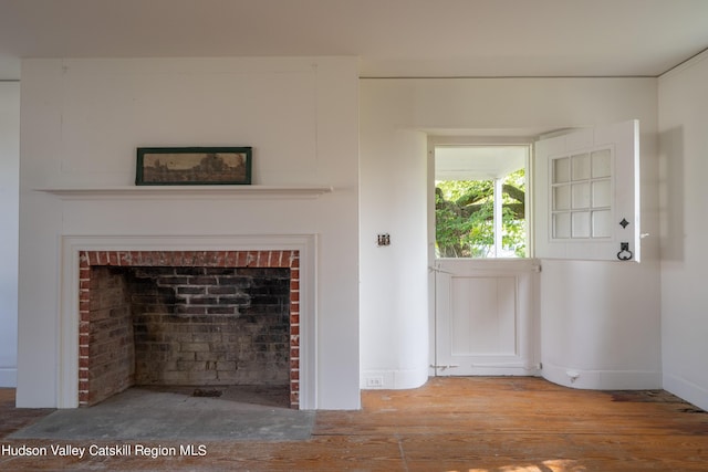 unfurnished living room featuring light hardwood / wood-style flooring and a brick fireplace