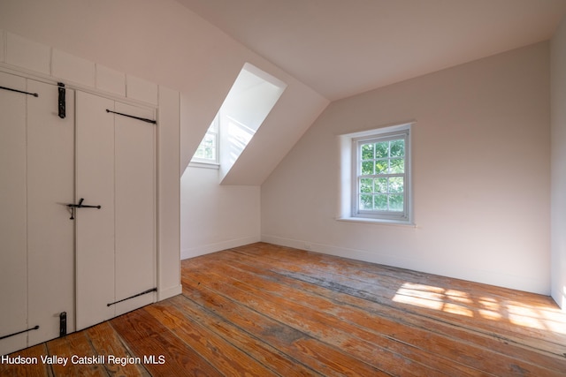 additional living space with light wood-type flooring and vaulted ceiling