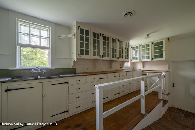 kitchen featuring tasteful backsplash, dark hardwood / wood-style flooring, white cabinetry, and sink