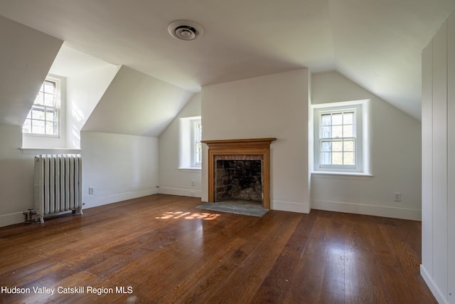 additional living space with dark hardwood / wood-style floors, radiator, and a healthy amount of sunlight