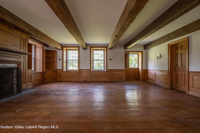 unfurnished living room with dark hardwood / wood-style flooring, beamed ceiling, and a healthy amount of sunlight