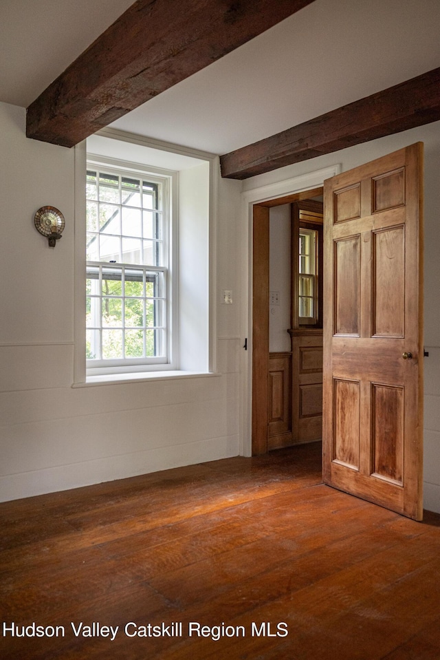 empty room with beam ceiling and dark wood-type flooring