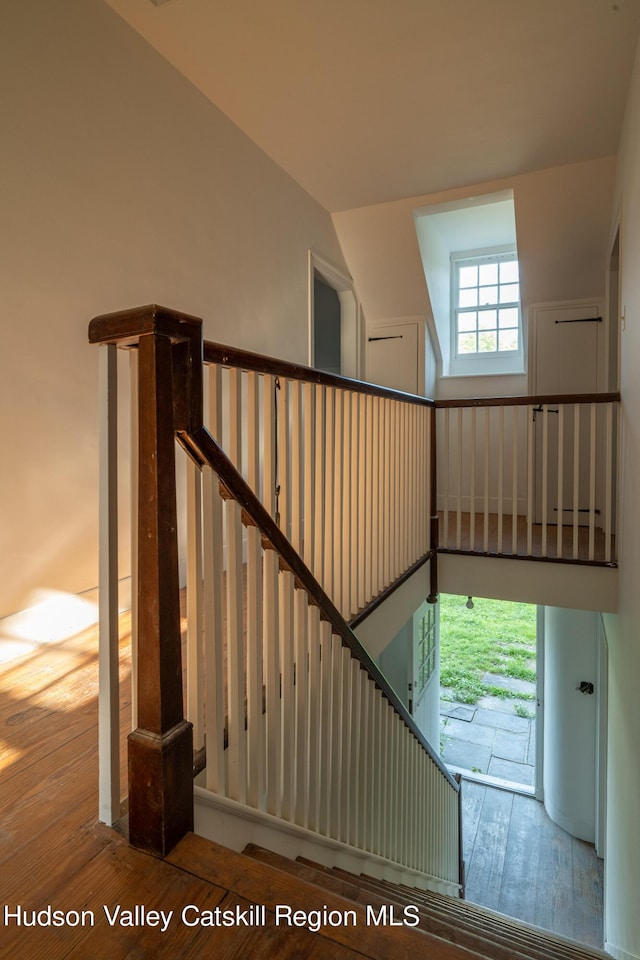 stairway with hardwood / wood-style flooring and lofted ceiling