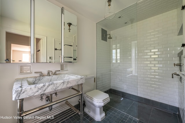 bathroom featuring a tile shower, tile patterned flooring, and toilet