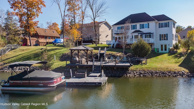 dock area with a gazebo, a water view, and a lawn