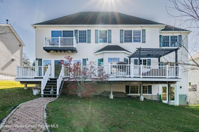 back of property with a deck, a pergola, and a yard