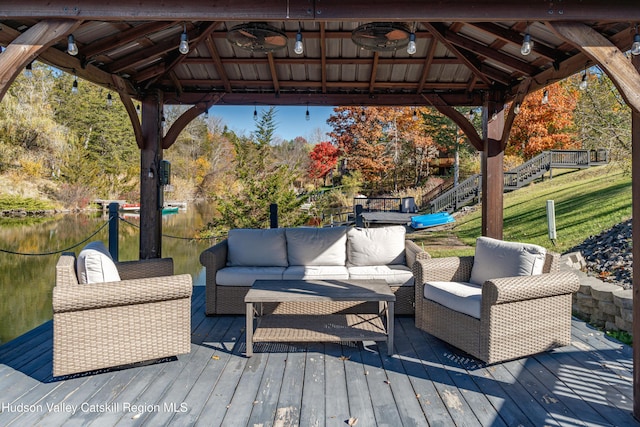 wooden terrace with a gazebo, an outdoor hangout area, a water view, and ceiling fan