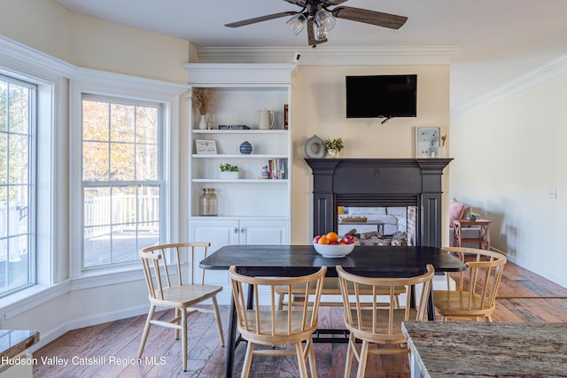 dining space featuring a multi sided fireplace, crown molding, ceiling fan, and wood-type flooring