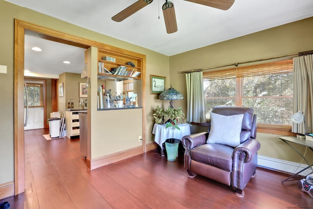 living area with a healthy amount of sunlight, wood-type flooring, and a baseboard radiator