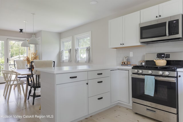 kitchen with kitchen peninsula, stainless steel appliances, and a healthy amount of sunlight